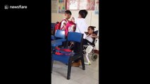 Touching moment two Filipino schoolboys help their classmate with cerebral palsy during break time