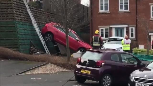Bizarre moment car crashes and ends up propped against fence vertically