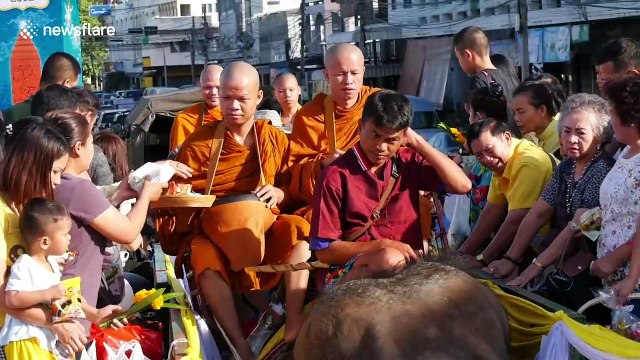 Thai monks ride elephants while receiving donations to mark the start of Buddhist Lent