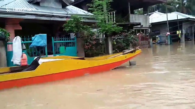 Rescuers travel in boats around flooded town in the Philippines in search for trapped residents