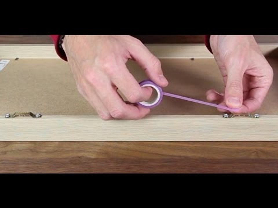 Er klebt Tesafilm auf den Rücken des Bildes.