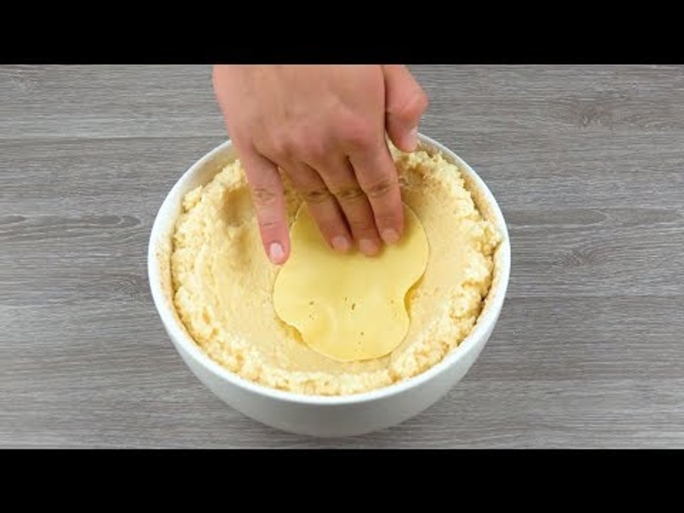 Ele coloca 10 fatias de queijo na tigela e despeja o risoto sobre elas. Isso vai ficar delicioso!