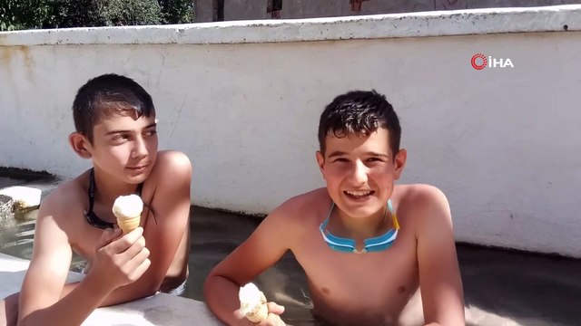 Sıcaklardan bunalan çocuklar köy meydanındaki su oluğunda serinliyor