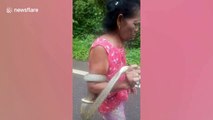 Bizarre moment grandmother, 75, carries live cobra down the road 'while in a trance'