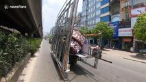 Tricycle carries huge iron frames through the streets of Vietnam