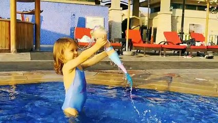 Little Mia playing with mermaid doll in swimming pool