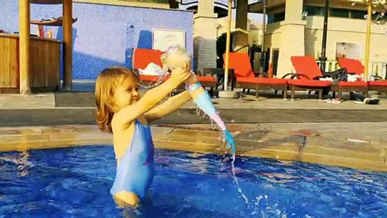 Little Mia playing with mermaid doll in swimming pool