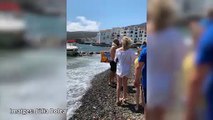 Embarrancada una barca en unes roques davant la platja de Cadaqués