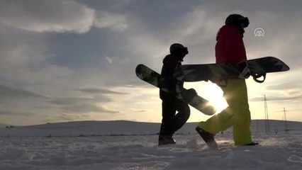 Köyde yaşayan gençlerden arazi aracıyla karda snowboard