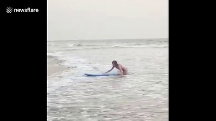 One surfer arrives gracefully and the other falls to shore in India