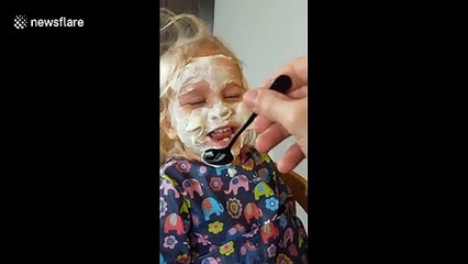 Two-year-old can't contain her laughter as dad paints her face in yoghurt