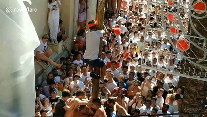 Residents in Spain battle to climb a pole during the infamous La Tomatina festival