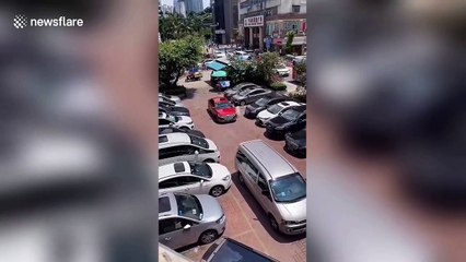 Chinese woman uses tape measure to make sure car fits in parking space
