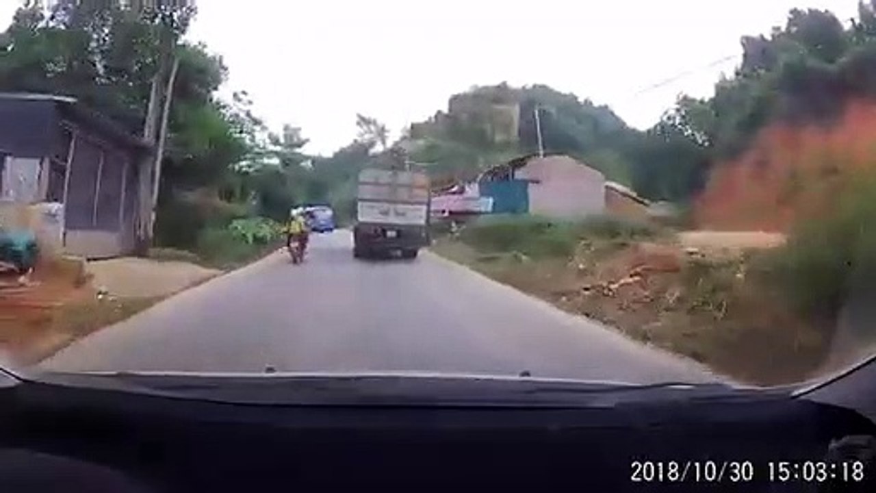 Xe máy lách qua khe hẹp giữa xe khách và xe tải như phim hành động