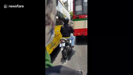 Reckless Thai motorcyclist swerves in between buses