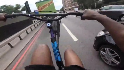 Des jeunes à vélo roulent en wheeling sur la route et l'un d'entre eux percute une voiture