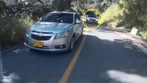 Une voiture double dans un virage et percute un motard