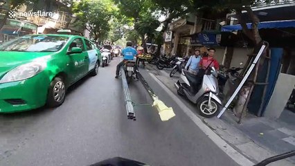 Man transports huge metal rods through Vietnam streets on motorbike