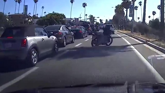 Un motard met un coup de pied dans le rétroviseur d'une voiture mais perd l'équilibre