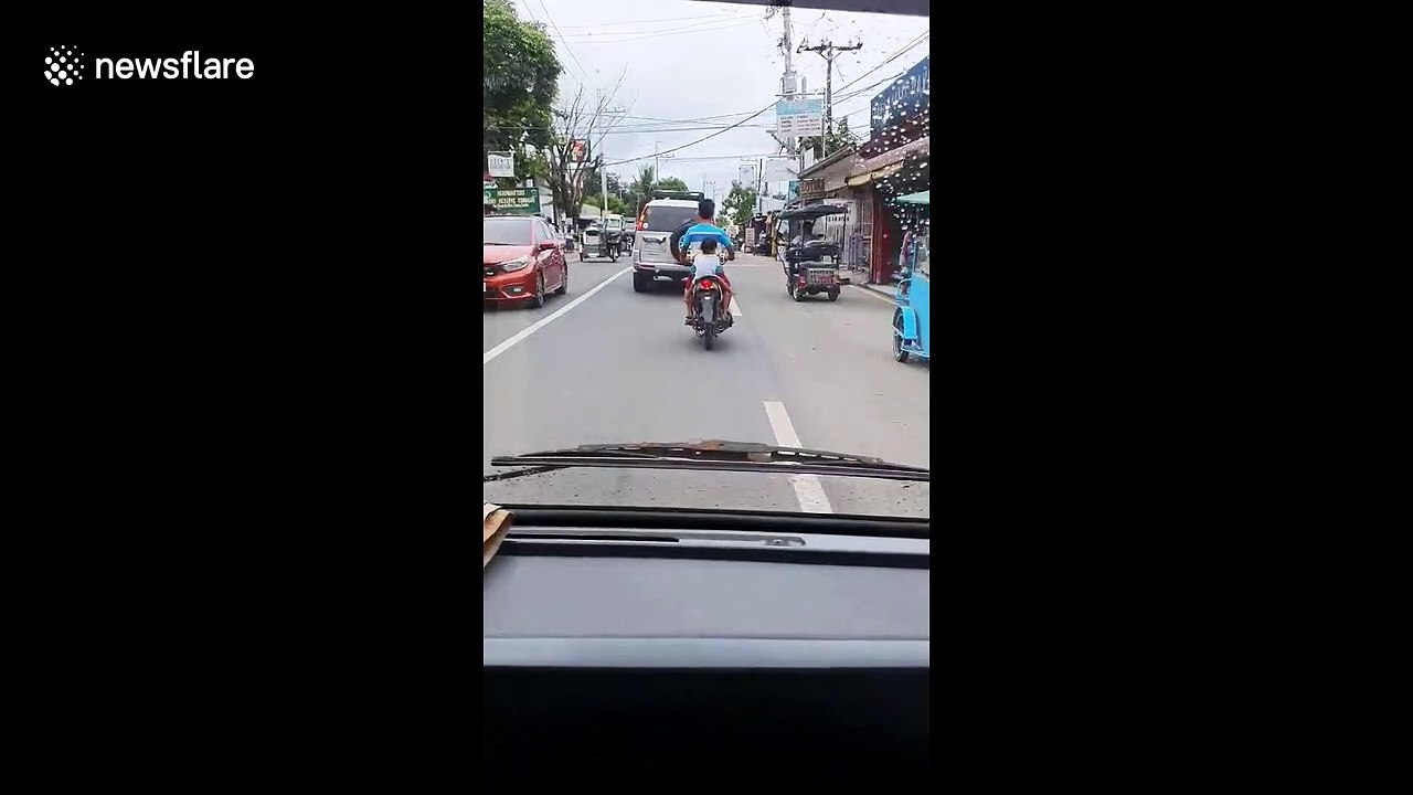 Filipino child rides pillion on motorcycle