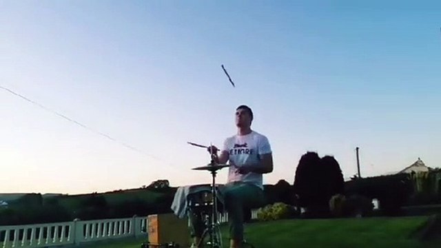 Il joue de la batterie en jonglant avec ses baguettes
