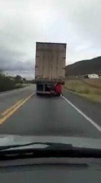 Deux hommes sont assis clandestinement à l’arrière d’un poids lourd en marche et profitent tranquillement du voyage.