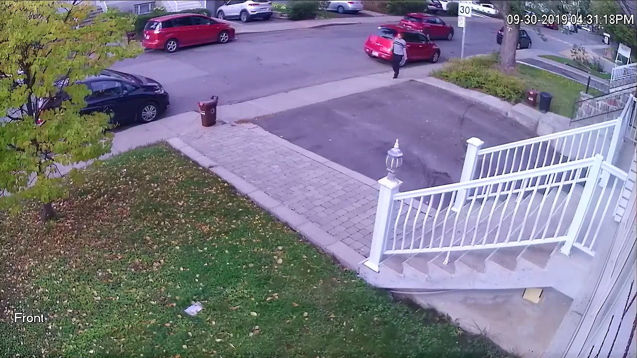 Une femme balance une poubelle sur une voiture