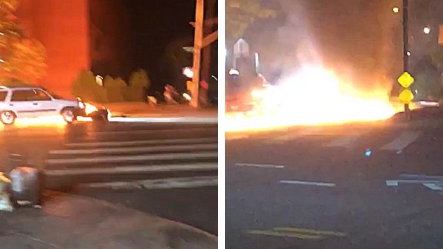 Une voiture pousse une moto en feu sur la route