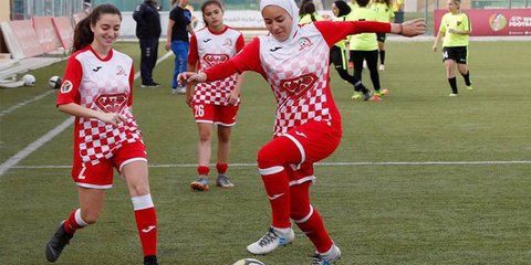 Estas futbolistas forman un corro alrededor de una rival para que se coloque bien el hiyab sin ser vista