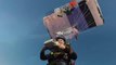 Two Skydivers Eat Pizza While Floating in Air Under Parachutes