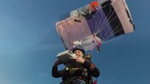Two Skydivers Eat Pizza While Floating in Air Under Parachutes