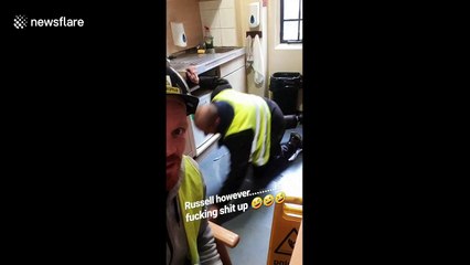 Plumber attempts to defrost freezer with screwdriver much to the disapproval of his colleague