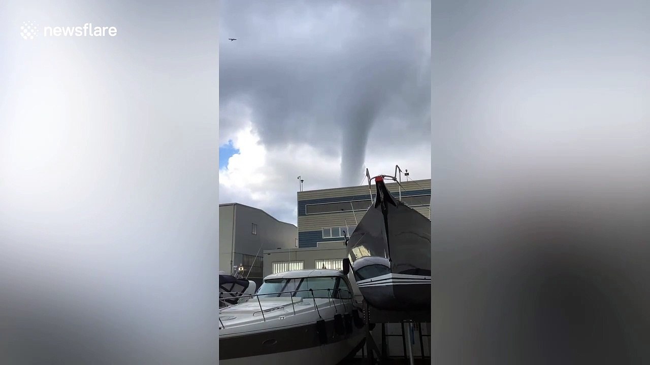 Huge waterspout towers above moored boats on the coast of Italy