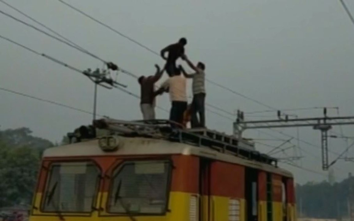 Youth creates high voltage drama holding overhead train wires : Watch Video | OneIndia News