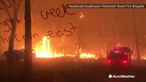 Firefighters drive down road surrounded by wildfire