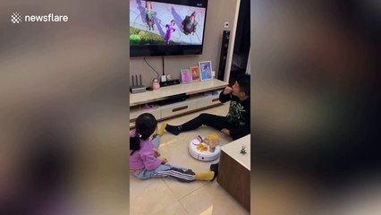 Creative father and daughter use robot vacuum to serve snacks and drink while watching TV together in China