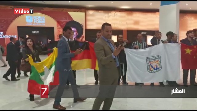 المشاركون بمنتدى الشباب يلتقطون صورا تذكارية بالأعلام