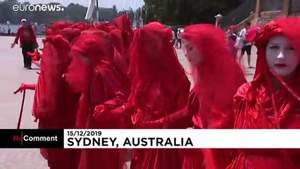 شاهد: نشطاء المناخ يتظاهرون أمام دار الأوبرا في سيدني بالزي الأحمر