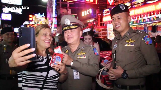 Police and gogo dancers in Santa costumes hand out gifts in Thailand