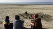 Varios hombres se entierran en una playa de Pakistán durante el eclipse solar para curarse