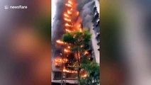 Dozens of people push car away from fire engine access after residential building catches fire in China