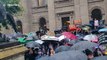 Melbourne demonstrators shelter under hundreds of umbrellas at climate protest