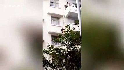 Un enfant suspendu au dessus du vide attaché à une corde pour récupérer un chat