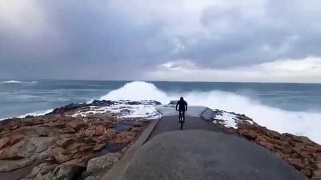 Ce cycliste se rapproche un peu trop près du bord de mer pendant la tempête en Espagne