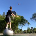 Guy Throws Rugby Ball in Basket From Considerable Distance While Balancing Himself Over Fitness Ball
