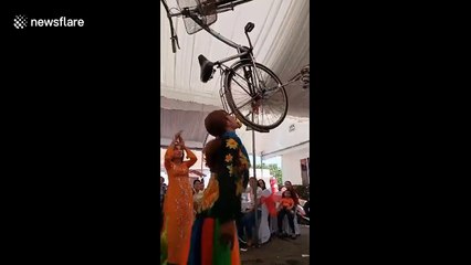 Vietnamese street performer dances while balancing bicycle on her mouth
