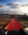 Une voiture miniature de course roule sur une piste incroyable dressée sur la plage.