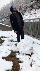 Man Throwing a Large Snowball into Water