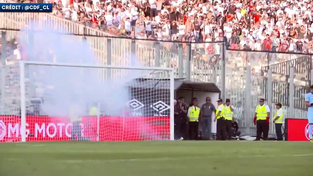 Un gardien ramasse un téléphone portable lors du chaud derby de Santiago au Chili