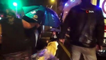 Motosikletten düşerek yaralanan kadını yağmurdan şemsiyelerle korudular